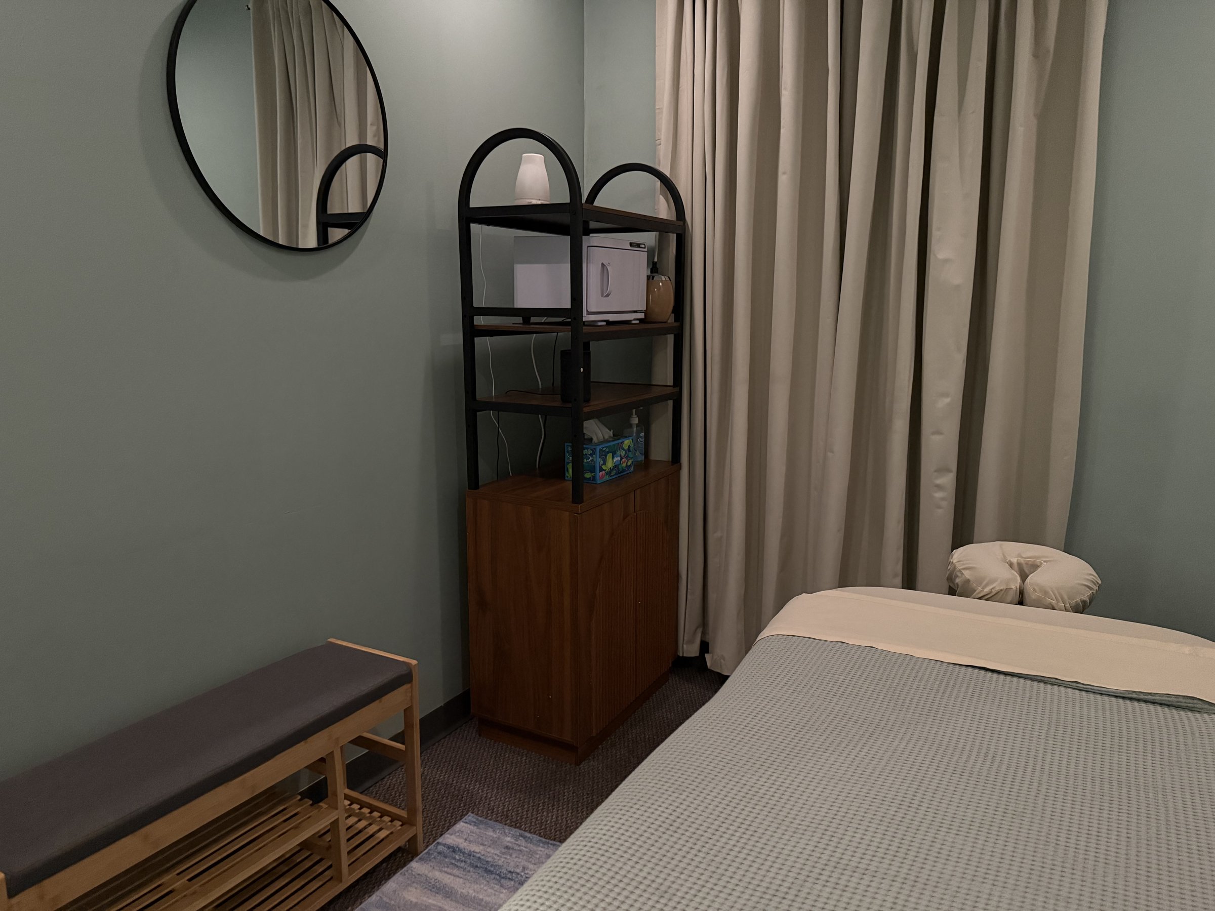 Private massage room with a prepared table, mirror, and shelving